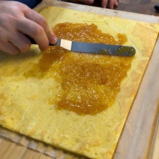 Una persona sta spalmando la marmellata su un pezzo di pane