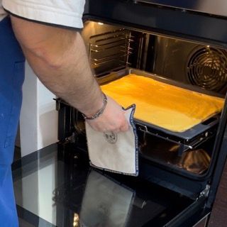 Un uomo sta pulendo l'interno di un forno con un panno