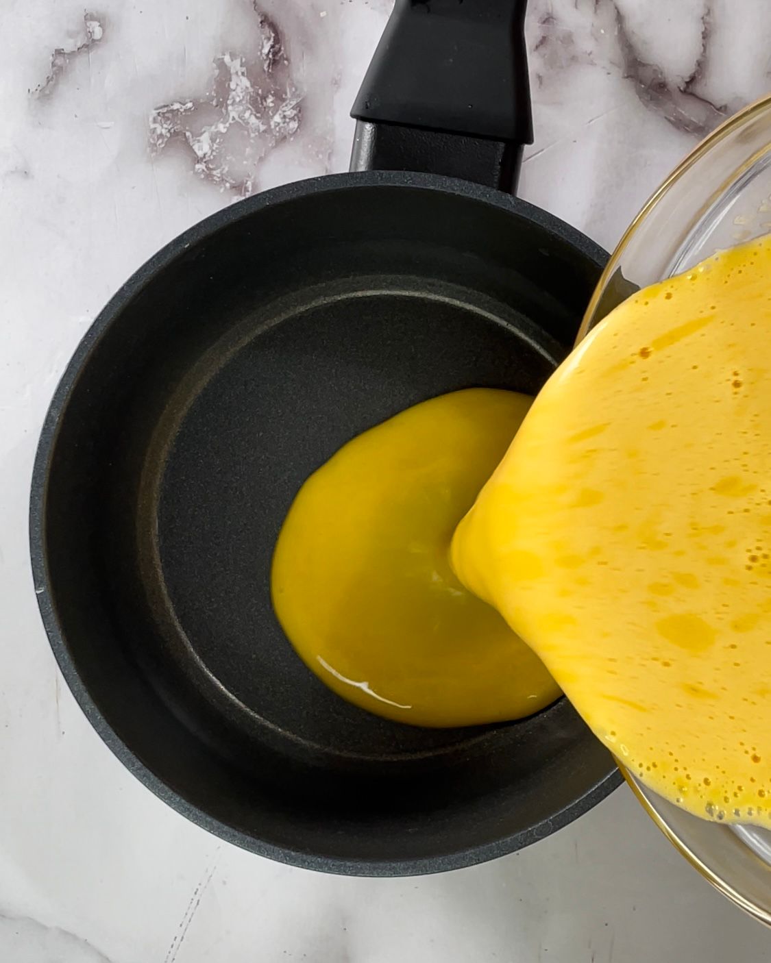 Un liquido giallo viene versato in una padella.