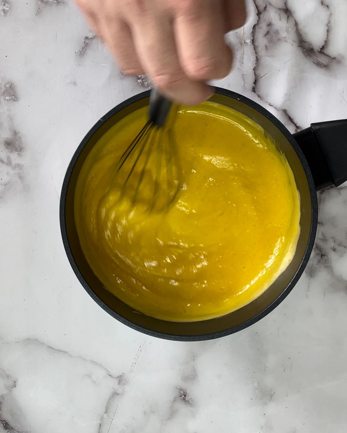 Una persona sta mescolando un liquido giallo in una pentola.