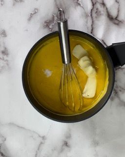 Una pentola di salsa gialla con dentro una frusta.