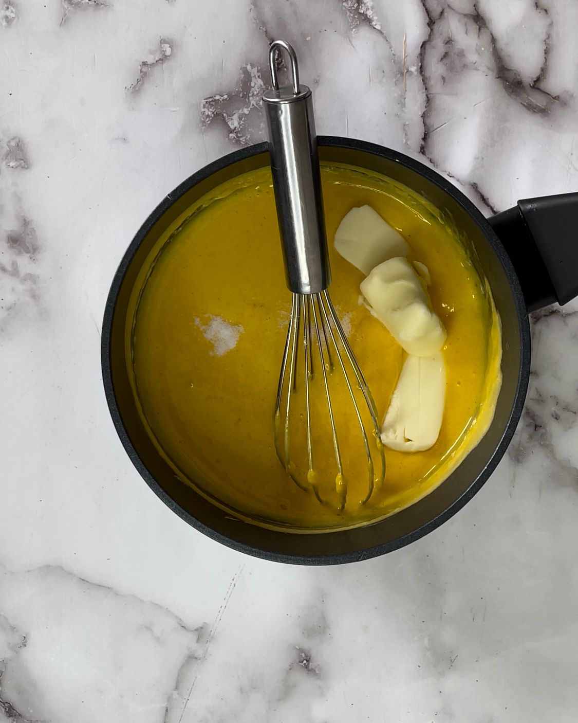 Una ciotola di liquido giallo con una frusta dentro