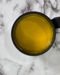 Una tazza di liquido giallo è appoggiata su una superficie di marmo.