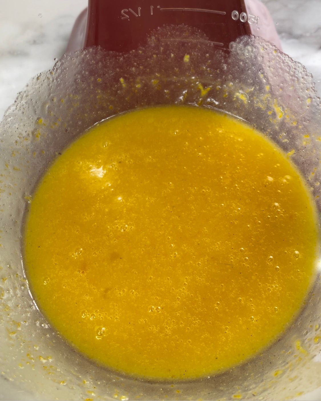 Un primo piano di un liquido giallo in una tazza graduata