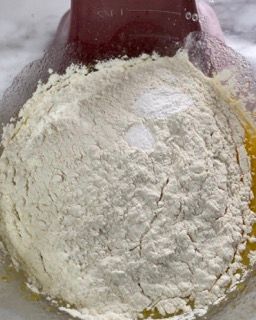 Primo piano di una ciotola di farina con una spatola dentro.