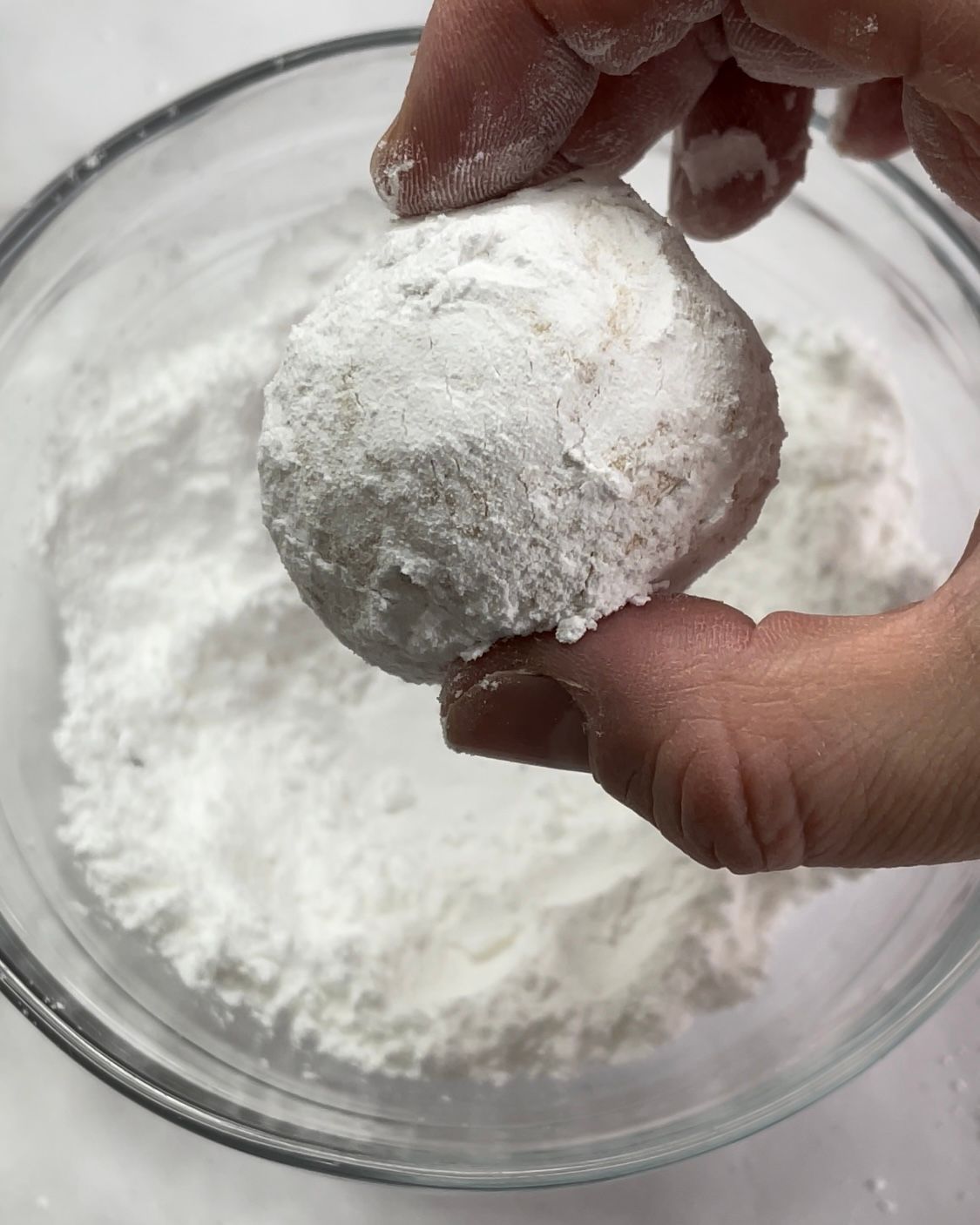 Una persona sta immergendo un biscotto nello zucchero a velo.