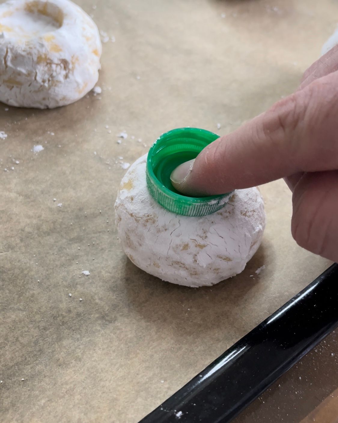 Una persona sta mettendo un coperchio verde su una ciambella