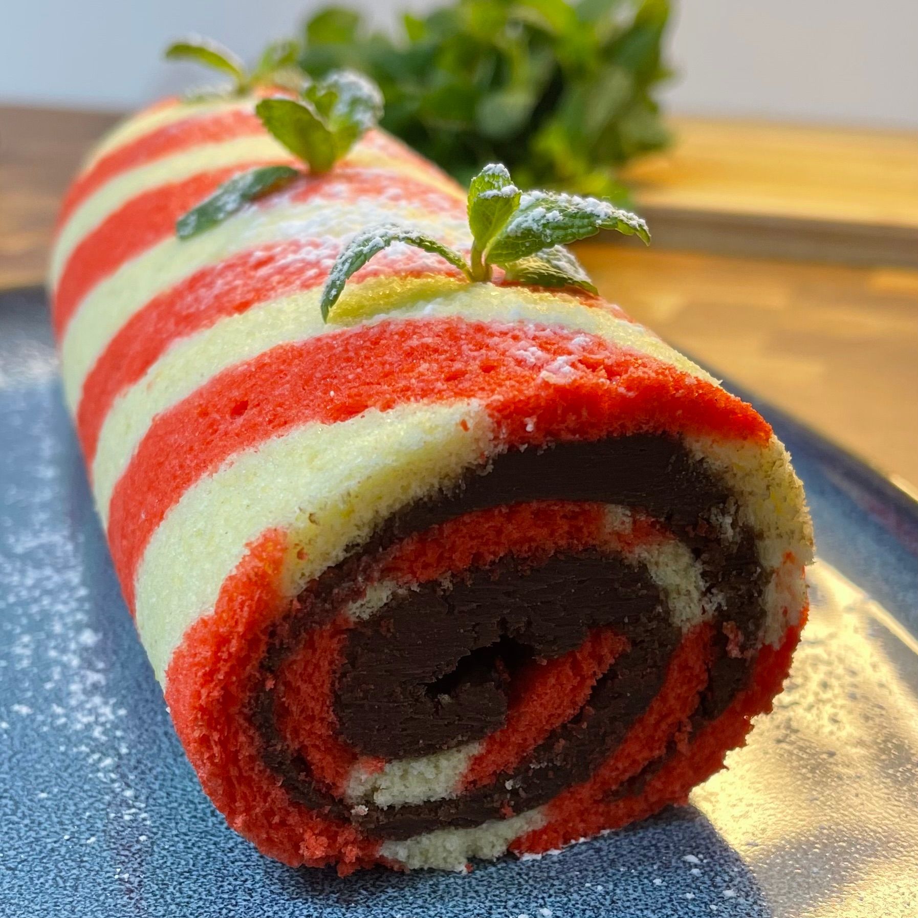 Un rotolo di torta a strisce rosse e bianche con foglie di menta sopra