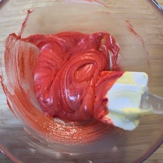 Una ciotola di glassa rossa con una spatola dentro