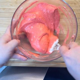 Una persona tiene in mano una coppetta di gelato rosa.