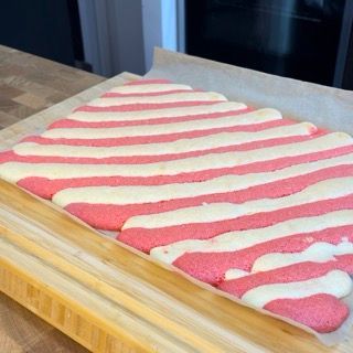 Un pezzo di torta a strisce rosa e bianche su un tagliere di legno
