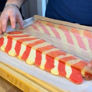 Una persona sta prendendo un pezzo di torta rossa e gialla