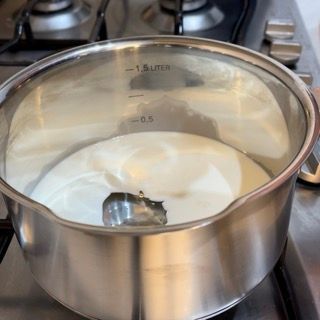 Una pentola di acciaio inossidabile con un coperchio di vetro riempito di liquido bianco