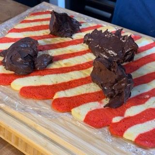 Biscotti a strisce rosse e bianche con glassa al cioccolato su un tagliere di legno