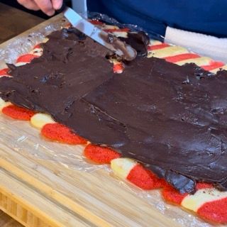 Una persona sta tagliando una torta al cioccolato su un tagliere