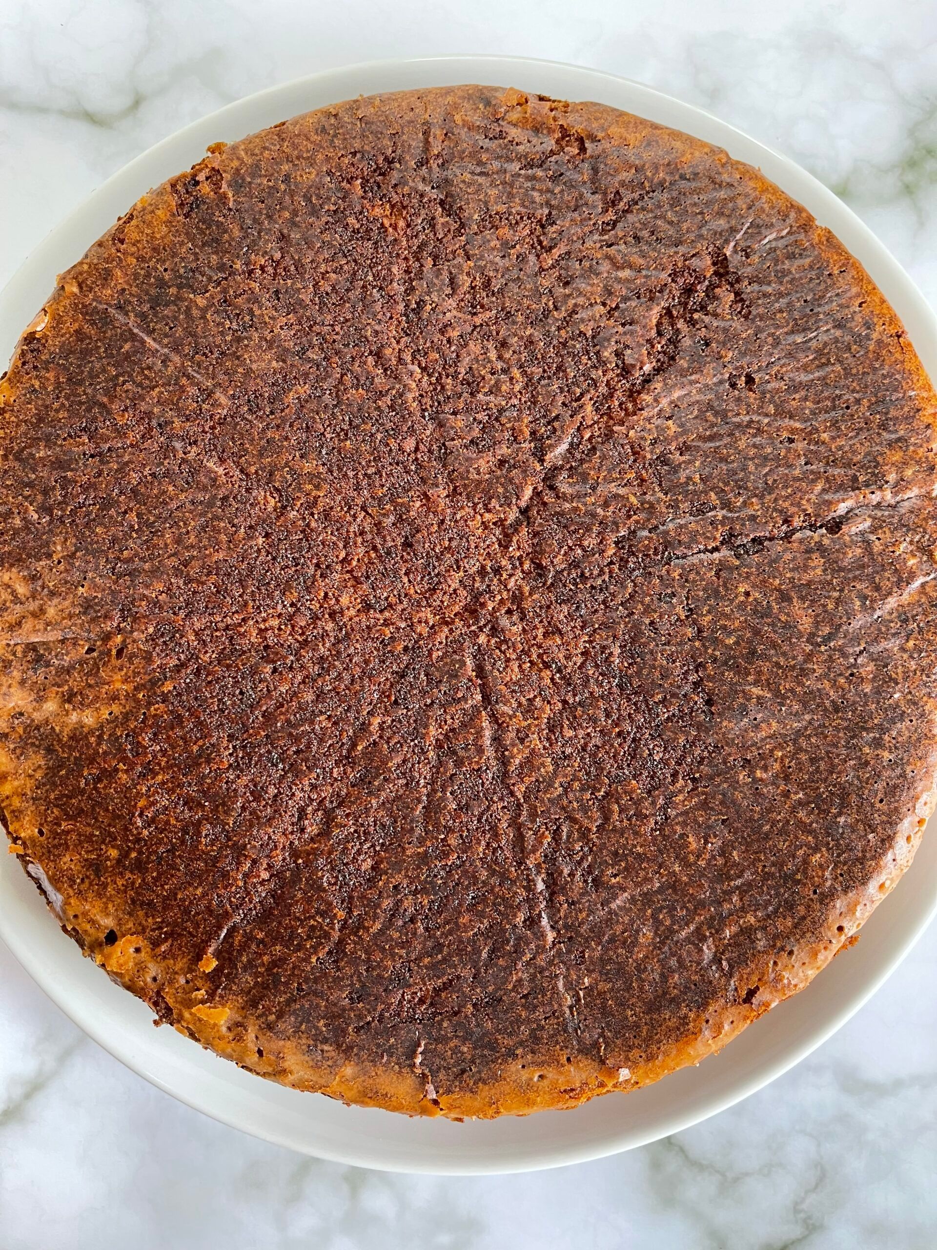 Una torta al cioccolato è su un piatto bianco su un tavolo.