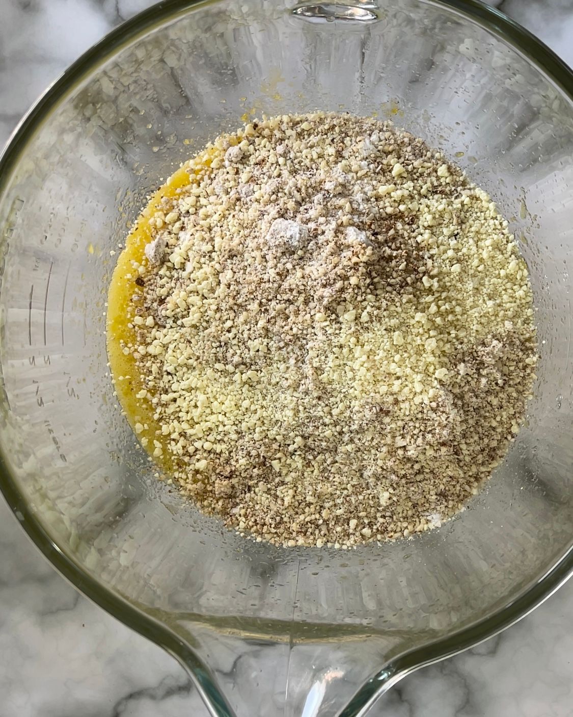 Una ciotola di vetro riempita con un composto di cereali e olio.