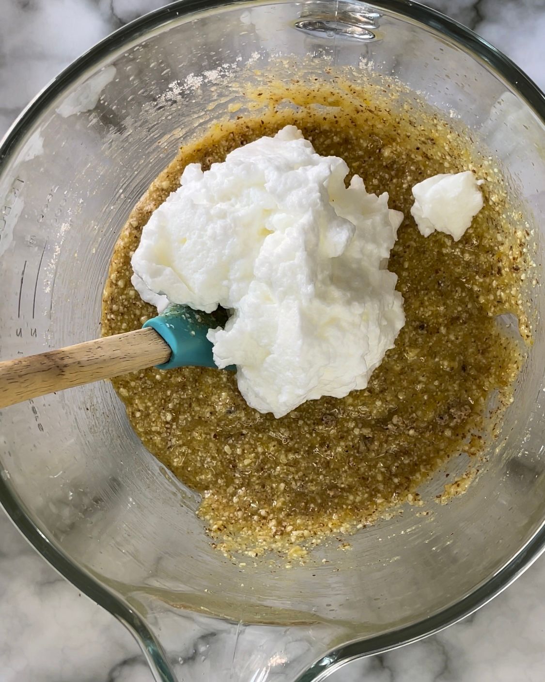 La panna montata viene aggiunta in una ciotola di vetro con un cucchiaio di legno.