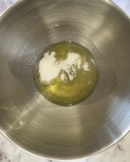 Una ciotola di metallo piena di un liquido giallo e di un liquido bianco.