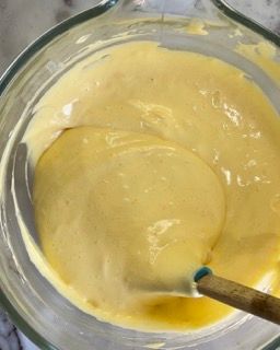 Una ciotola di salsa gialla con un cucchiaio di legno dentro