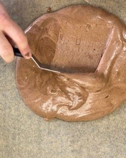 Una persona tiene una spatola sopra una ciotola di salsa al cioccolato.