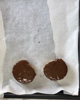 Due biscotti ricoperti di cioccolato su un pezzo di carta oleata