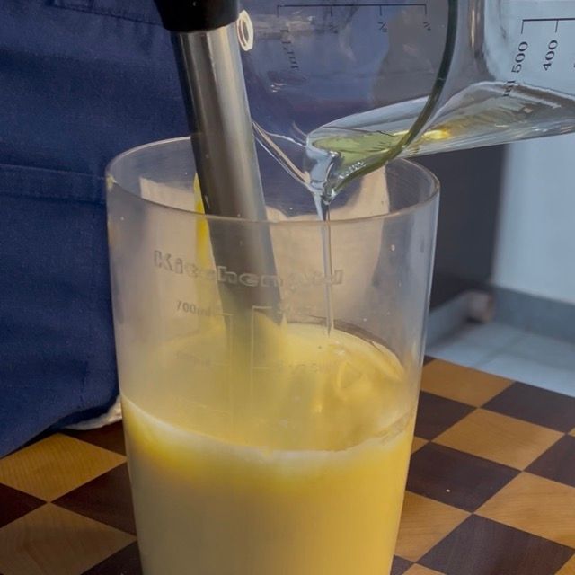 Olio versato a filo continuo mentre il frullatore monta la maionese.