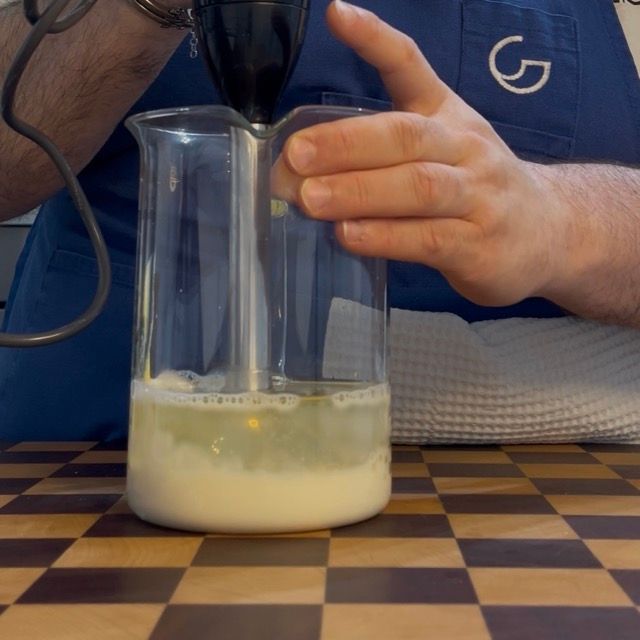 Minipimer posizionato fermo sul fondo del bicchiere, a contatto con il latte di soia.