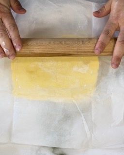 Il panetto di burro steso tra due fogli di carta da forno.