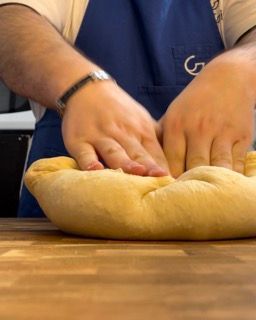 Mani che pirlano l'impasto formando una palla liscia.