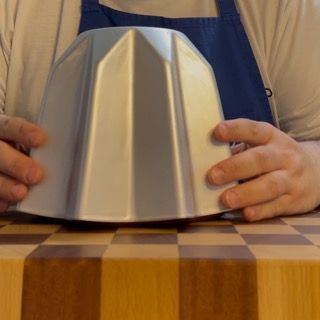 Una persona che tiene una ciotola d'argento su un tavolo di legno