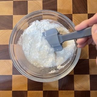 Una persona sta mescolando qualcosa in una ciotola con una spatola