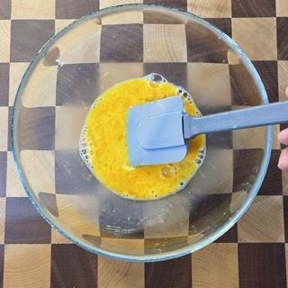 Una persona sta mescolando le uova in una ciotola con una spatola