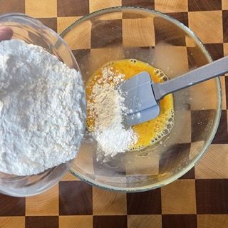 Una ciotola di farina viene versata in una ciotola di uova
