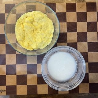 Una ciotola di purè di patate accanto a una ciotola di latte su un tagliere a scacchi