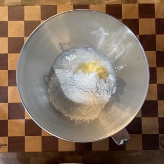 Una ciotola di metallo piena di farina e burro su una tavola a scacchi