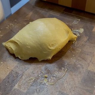 Un pezzo di pasta è appoggiato su un tagliere di legno