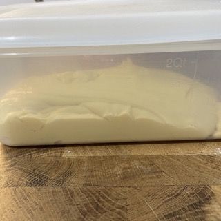 Un contenitore di plastica pieno di polvere bianca è appoggiato su un tavolo di legno.