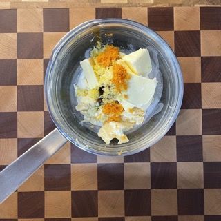 Una padella piena di burro e scorza d'arancia su un tavolo a scacchi