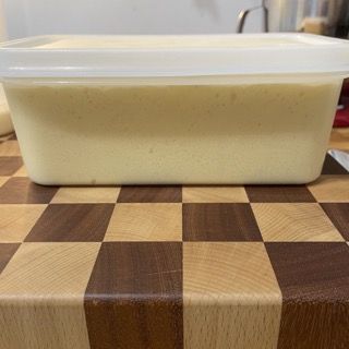 Un contenitore di gelato è appoggiato su un tagliere di legno