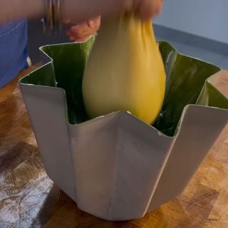 Una persona tiene in mano un oggetto giallo in una ciotola bianca.