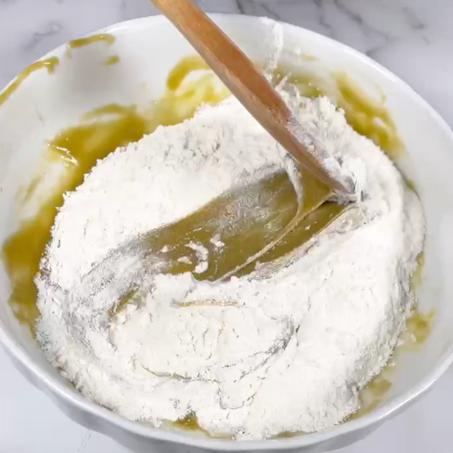 Una ciotola di farina con un cucchiaio di legno dentro.