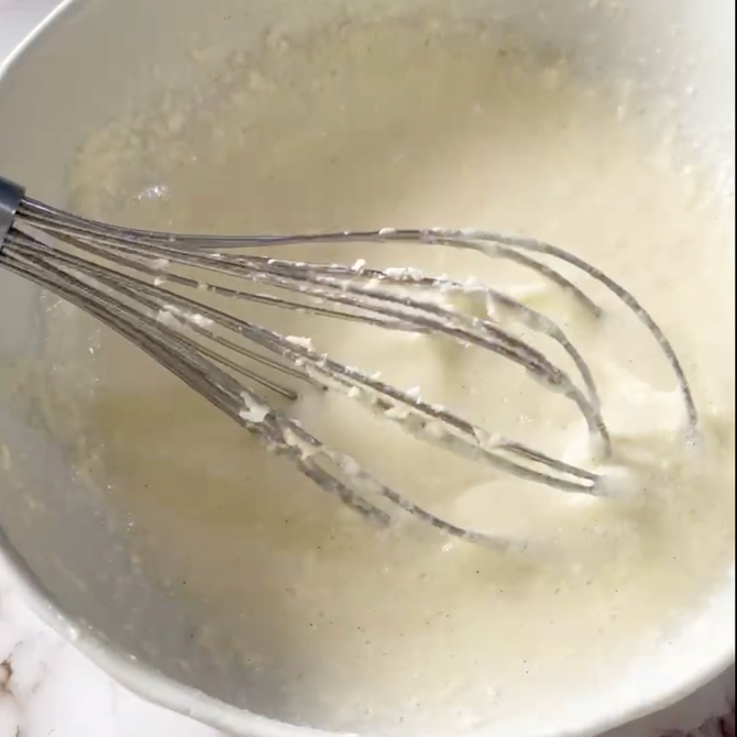 Una frusta è in una ciotola di liquido bianco