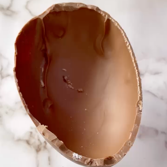 Un uovo di cioccolato rotto è appoggiato su una superficie di marmo