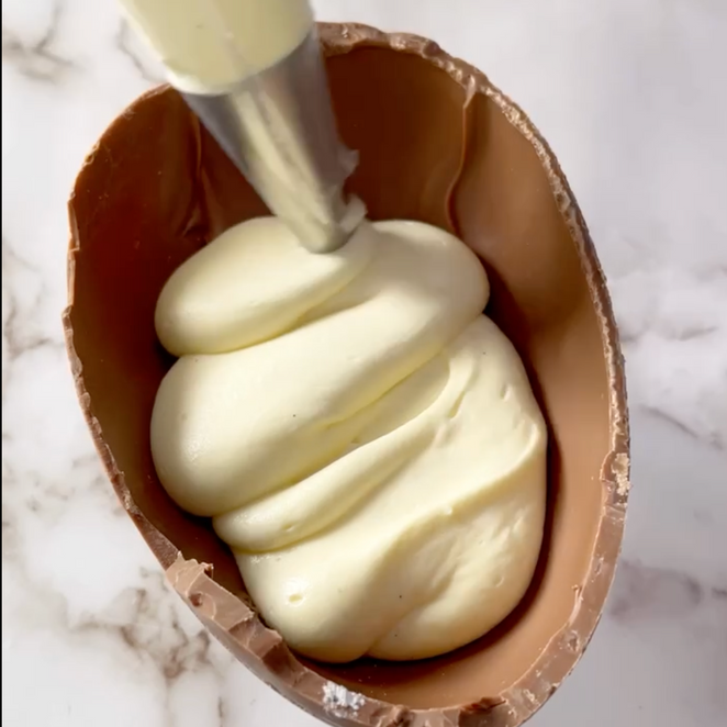 La glassa bianca viene versata in un uovo di cioccolato