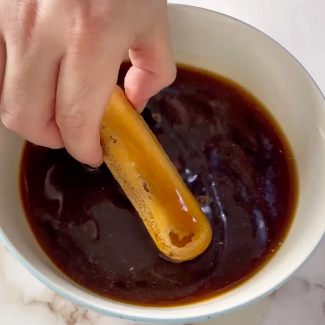 Una persona sta immergendo un bastoncino in una ciotola di salsa