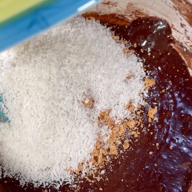 Il cocco viene versato in una ciotola di impasto al cioccolato