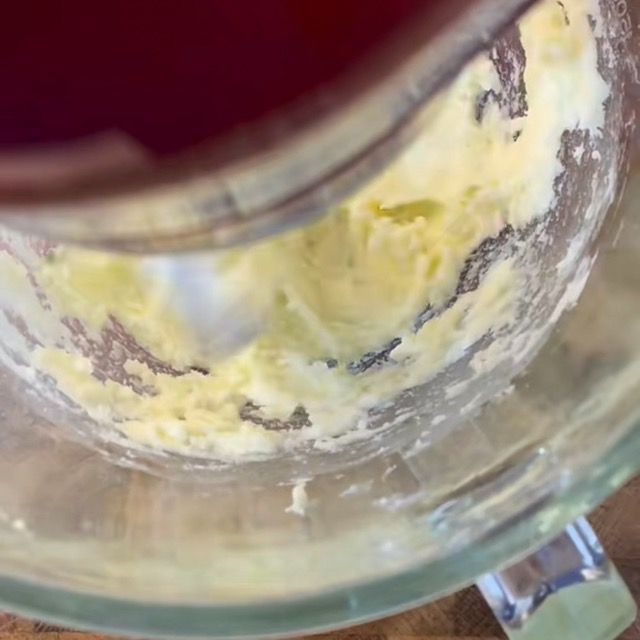 Crema di burro morbido e zucchero lavorata con una spatola in una ciotola capiente.