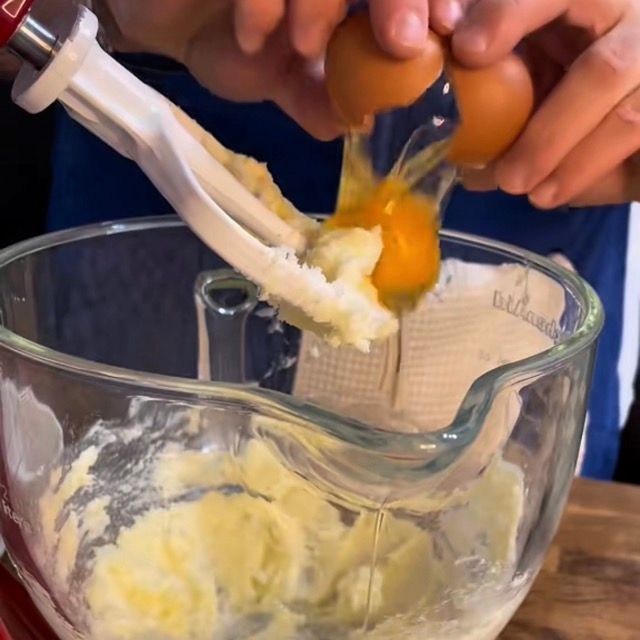 Uova intere versate nella ciotola con la crema di burro e zucchero.