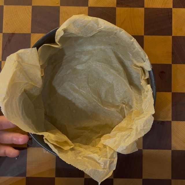 Teglia per cheesecake perfettamente foderata con bordi alti di carta forno